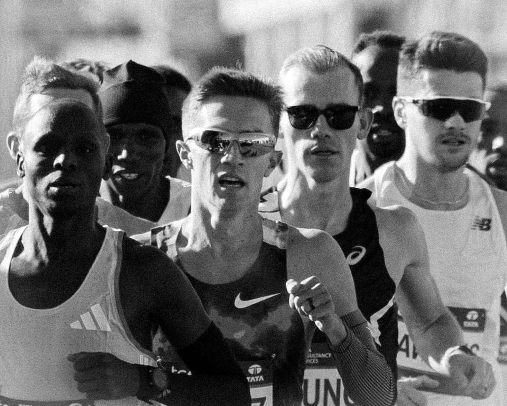 Black and white photo of elite male marathon runners from Adidas, Nike, ASICS and New Balance in close formation during NYC Marathon.