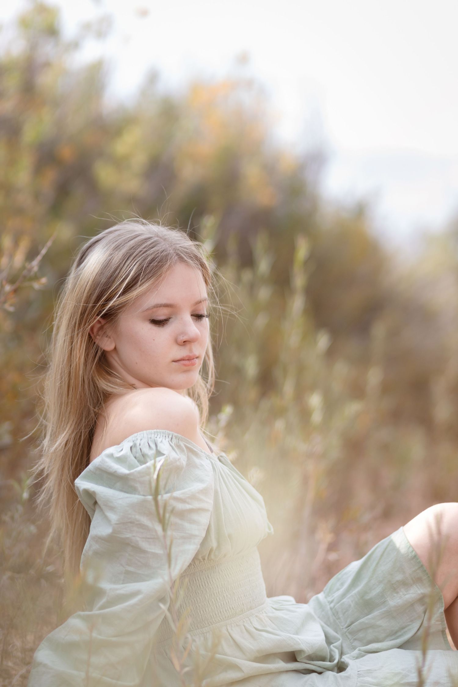 Person in vintage-style dress poses in field during golden hour.