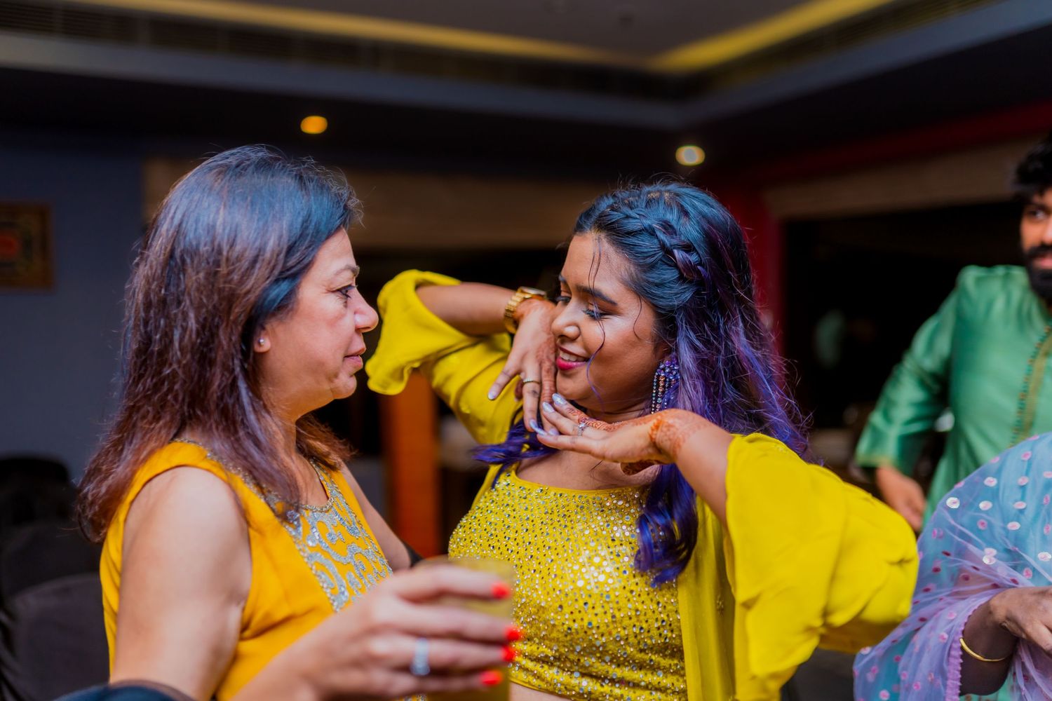 Two people in yellow outfits sharing an animated moment during a celebration.