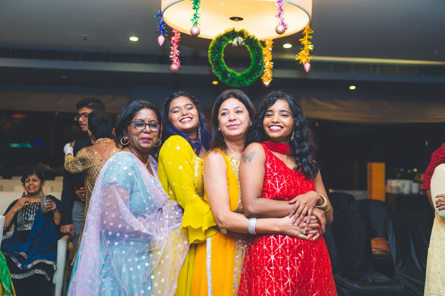 Group photo of guests in vibrant traditional attire under decorative lighting.