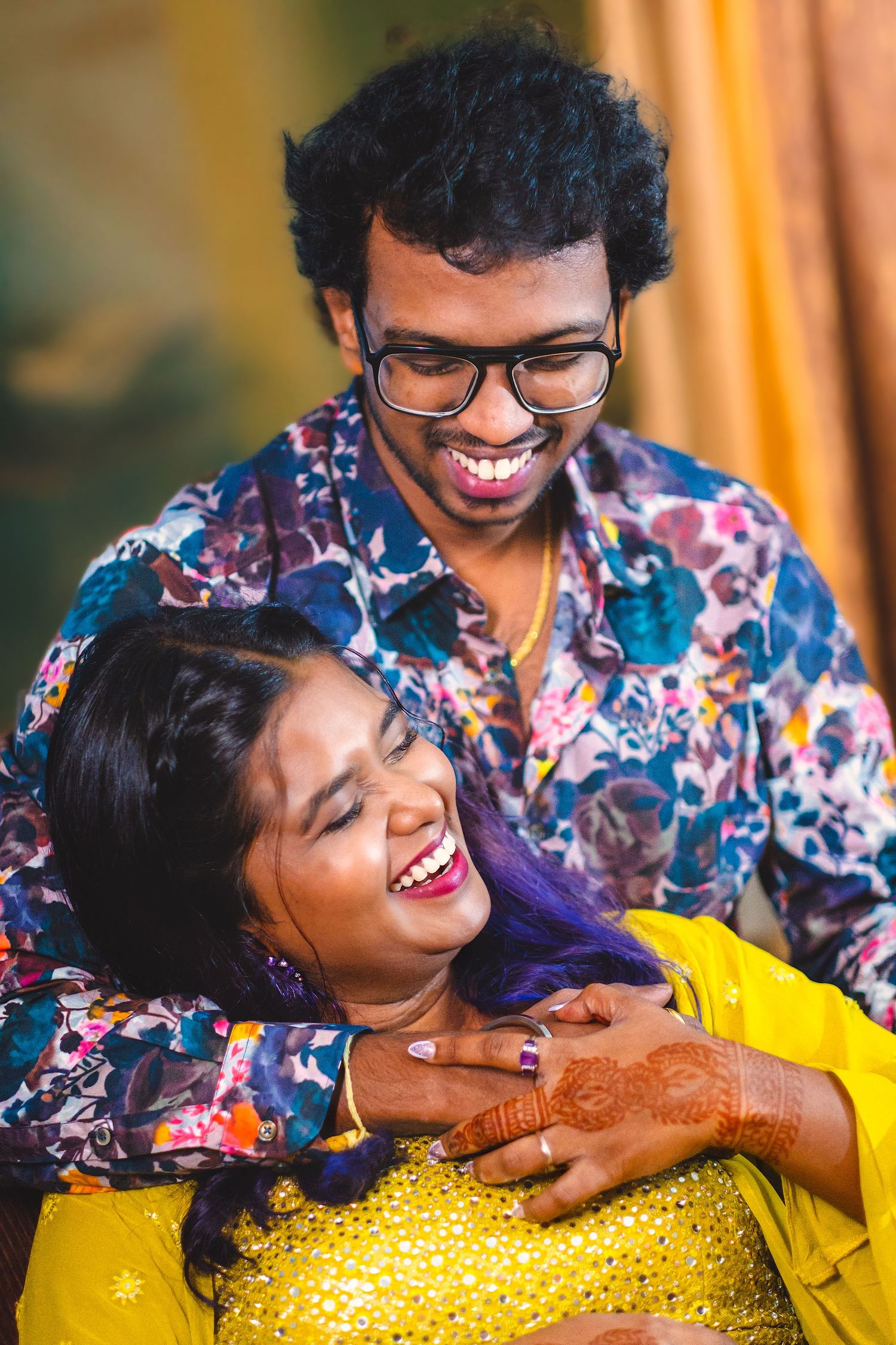 A joyful couple in colorful outfits share a candid laughing moment together.