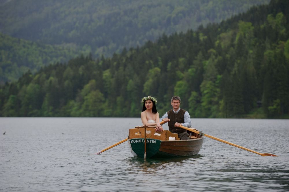 Engagement couple rowing a wooden boat on a mountain lake, romantic elopement atmosphere