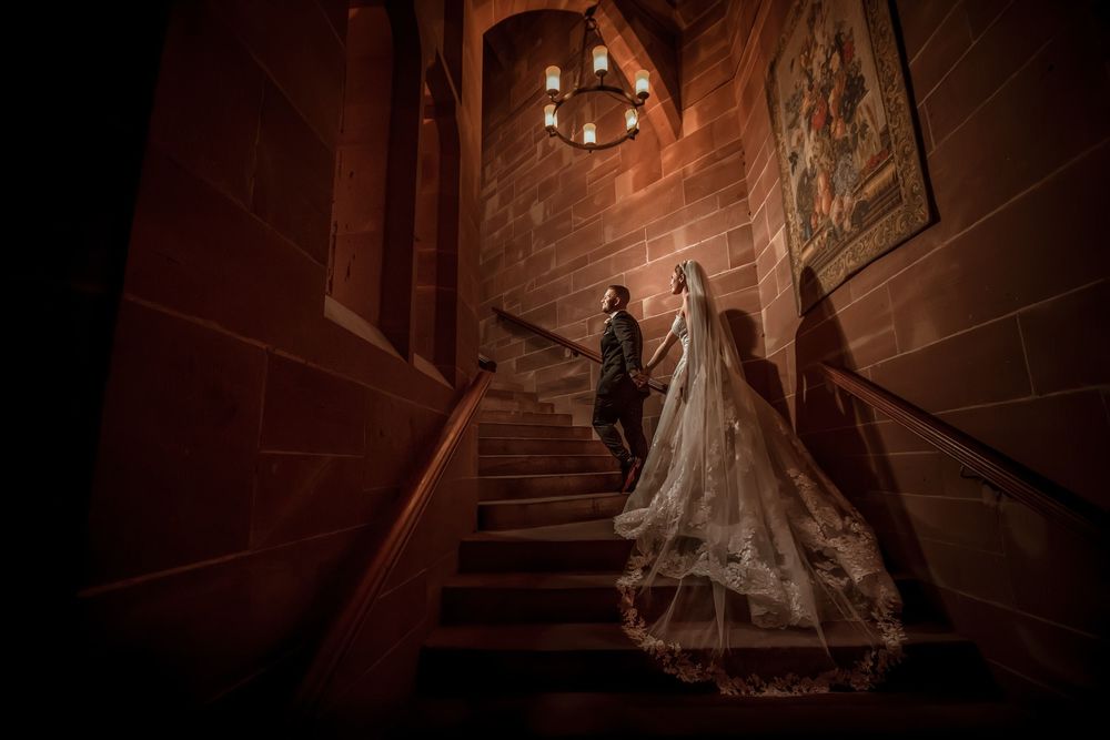 A dramatic sequence of wedding dress photos in a dimly lit grand staircase with moody lighting and flowing fabric.