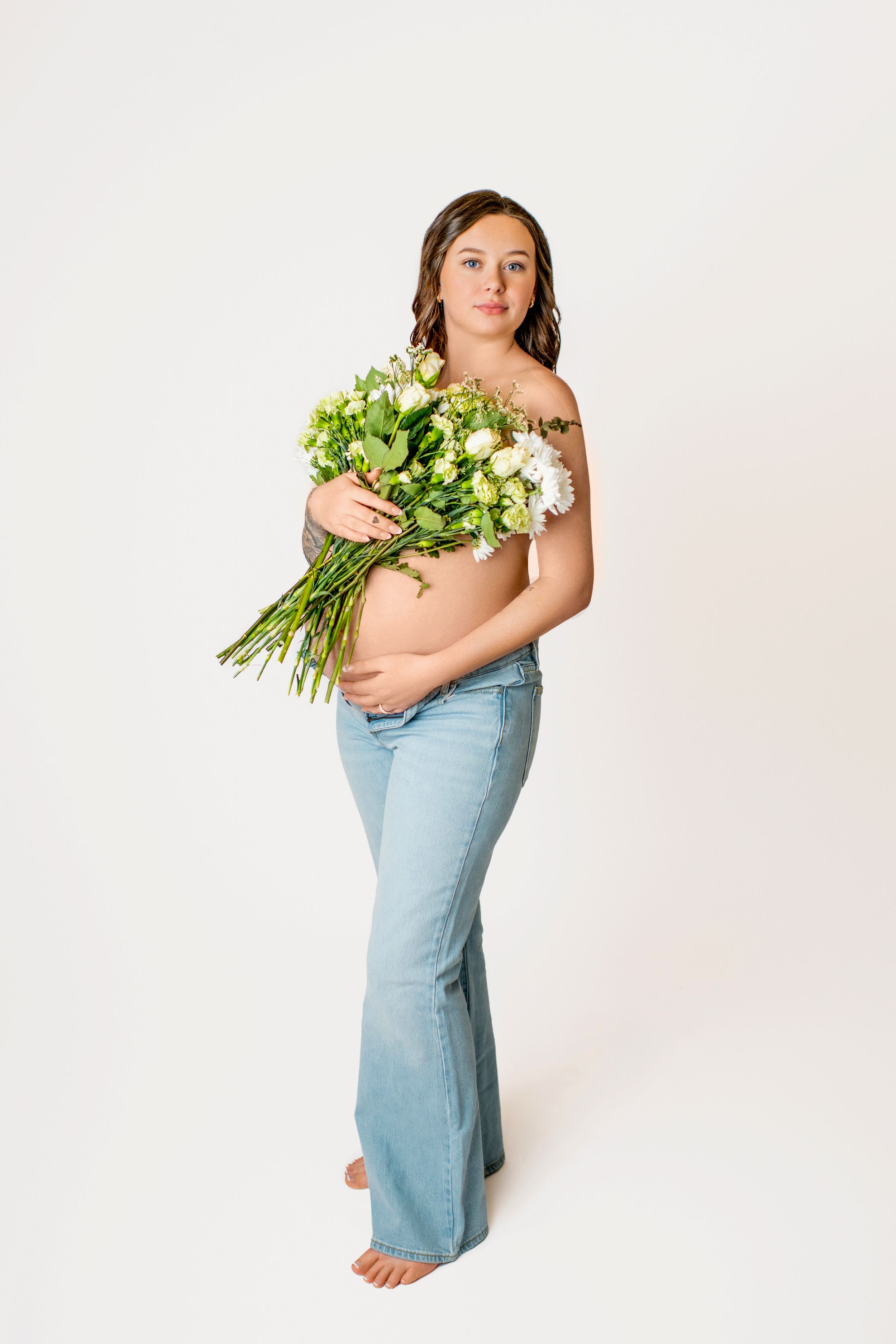 Three artistic portraits showing a figure in light denim dress holding a bouquet of fresh white flowers against a neutral backdrop.