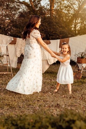 A joyful sequence of people in white dresses dancing and twirling together in a backyard with laundry hanging behind them.