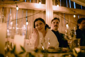 Group of friends enjoying drinks and conversation at a dimly lit restaurant with warm ambient lighting.