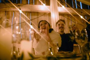 Couple shares joyful laughter at wedding reception under warm glowing lights.