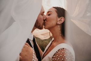 A tender kiss shared between a couple under a delicate wedding veil during their intimate ceremony.