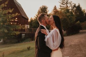Romantic sunset moment at rustic barn venue with evergreen trees in background.