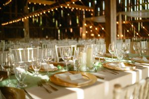 Elegant wedding reception table setting with string lights and gold charger plates.