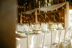 Wedding reception venue with white chairs and draped fabric under ambient lighting.