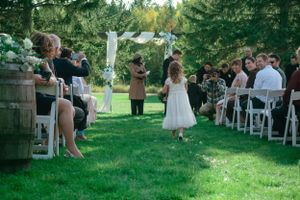 A couple exchanges vows during an intimate garden wedding ceremony surrounded by guests on a lush green lawn.