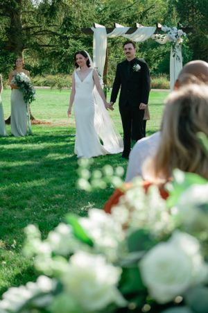 An outdoor garden wedding ceremony with white floral arch and elegant decorations.