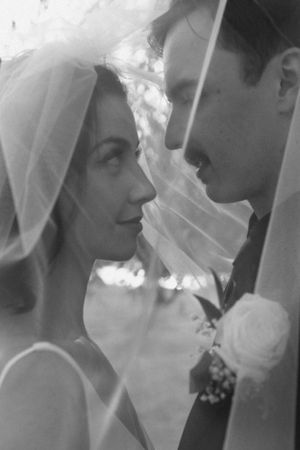 Black and white romantic photo of newlyweds sharing an intimate moment through a delicate veil.