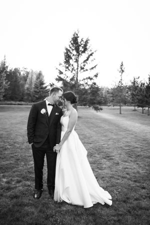 A romantic black and white wedding portrait of a couple standing together in an outdoor garden setting.