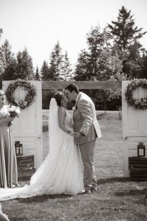 A romantic outdoor wedding ceremony in black and white with rustic white doors, wreaths and lanterns as decorations.