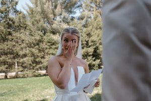 An emotional first look reaction during a sunny outdoor wedding ceremony.