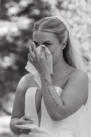 Black and white photo of emotional moment with tissue at wedding ceremony.
