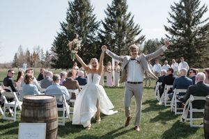 Outdoor wedding ceremony with rustic barrel decor and evergreen trees in background.