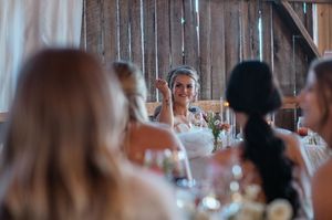 Wedding reception gathering in rustic barn venue with string lights.