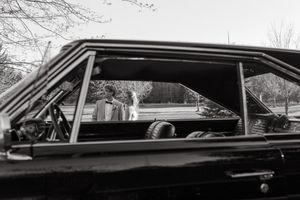 Black and white photograph of a car's window and side profile.
