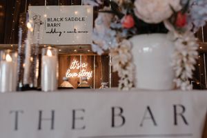 Illuminated candles and signage at an elegant wedding bar setup with soft romantic lighting and decorative details.