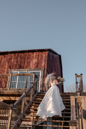 Rustic wooden building exterior with a staircase and warm lighting at dusk against a blue sky backdrop.