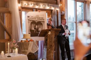 Wedding reception speech being given at a rustic wooden podium decorated with candles and vintage decor.