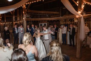 Wedding celebration inside a rustic barn decorated with twinkling lights and fabric draping.