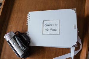 A wedding keepsake book titled 'Letters to the Bride' with vintage camera on wooden surface.