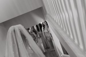 Black and white view of formal outfits hanging on a stairway railing.