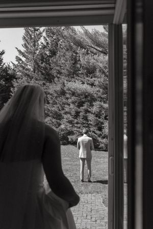 Artistic black and white photo showing two people through a doorway with trees in background.