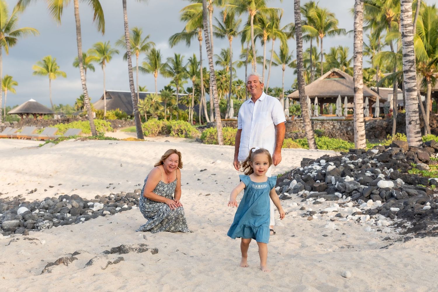 Family enjoying a tropical beach vacation with palm trees and black lava rocks in Hawaii.