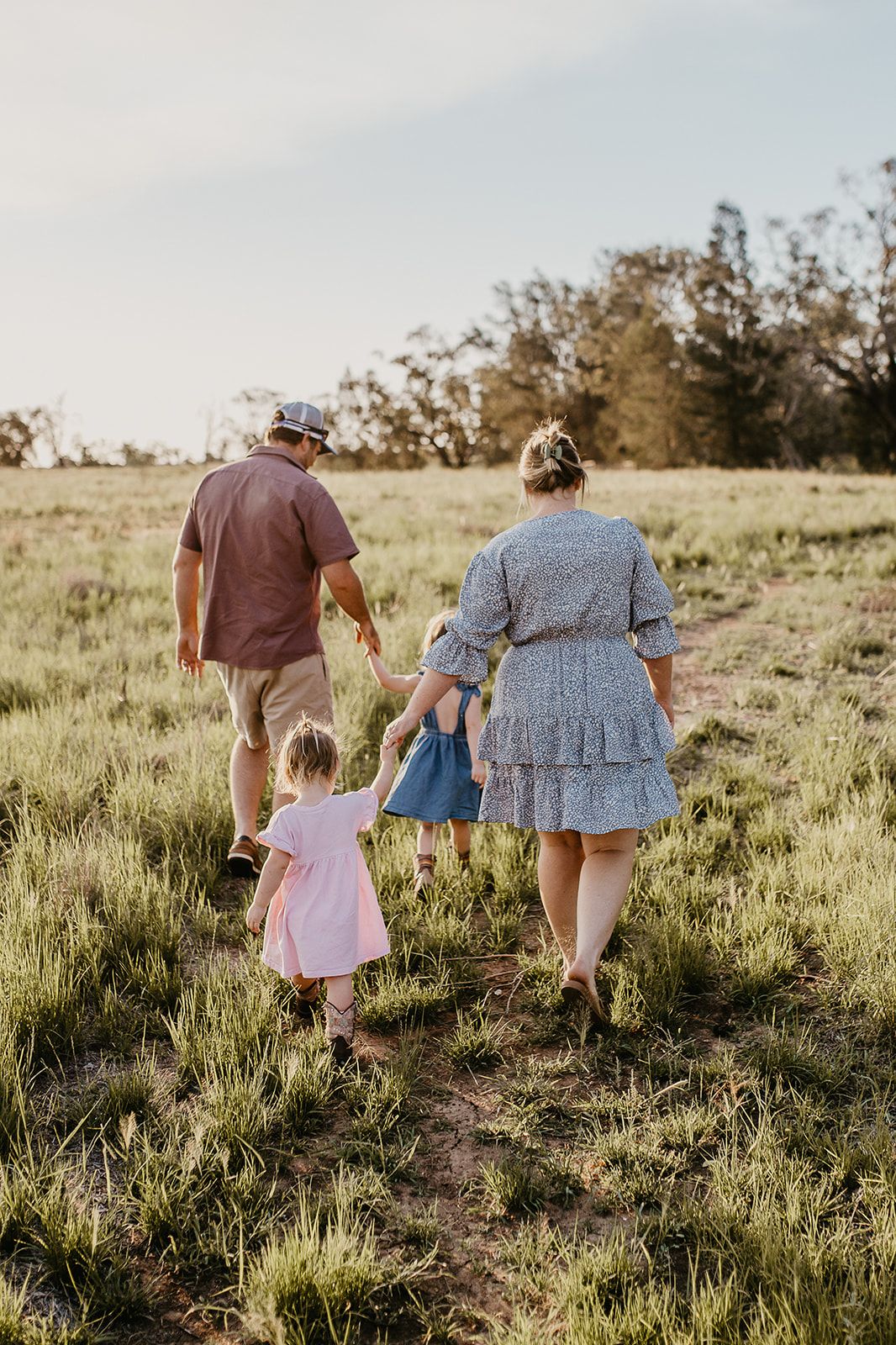 family holding hands walking through rural paddock