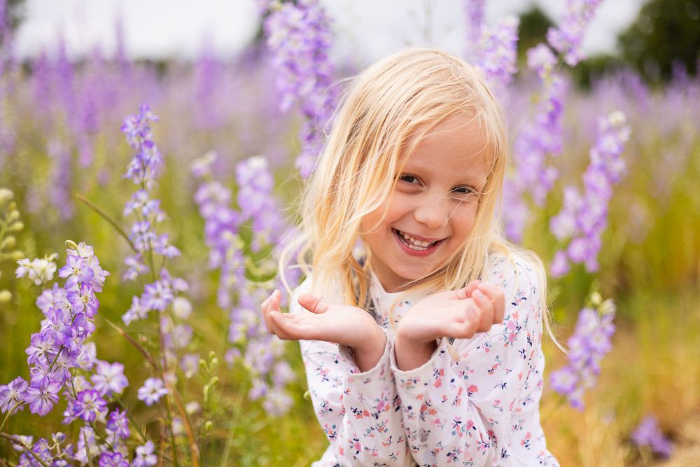 Portrait photo of a young girl with a backdrop of purple flowers.