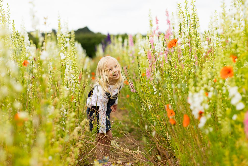 Portrait photo of a young girl amongst a field of tall wild flowers.