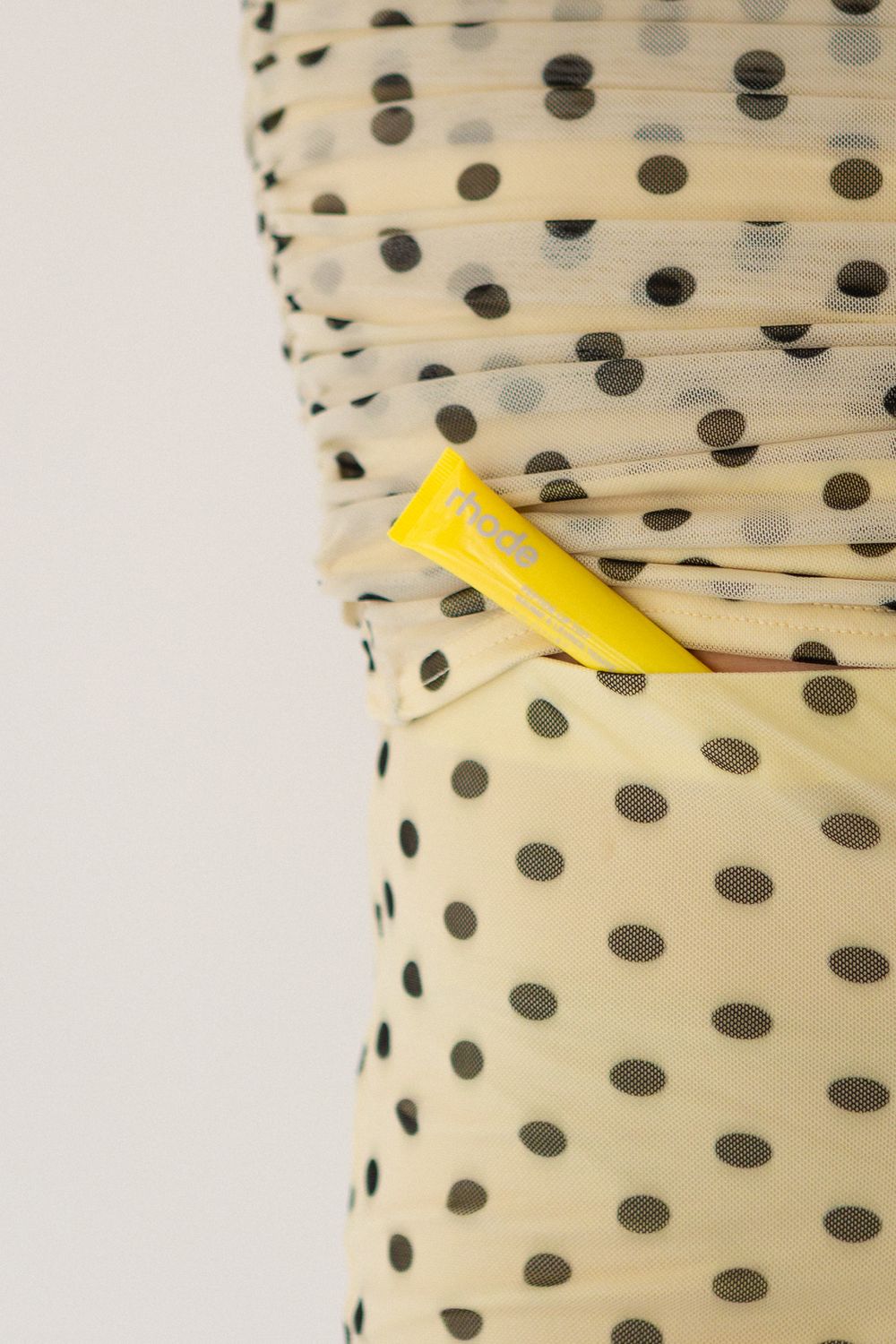 Close-up of a cream polka dot fabric with a yellow zipper detail.