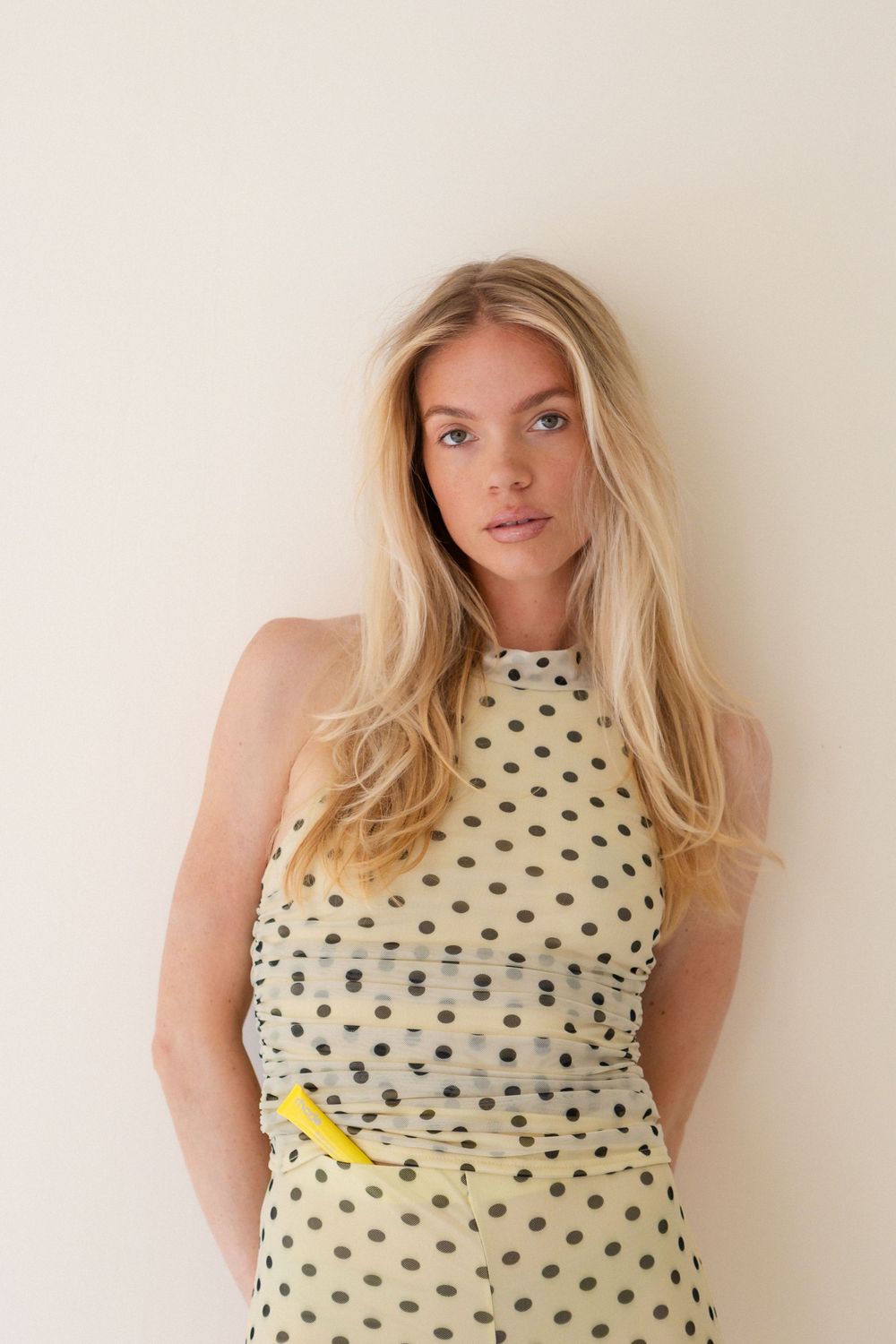 A polka dot halter dress in cream and black with gathered fabric detail.