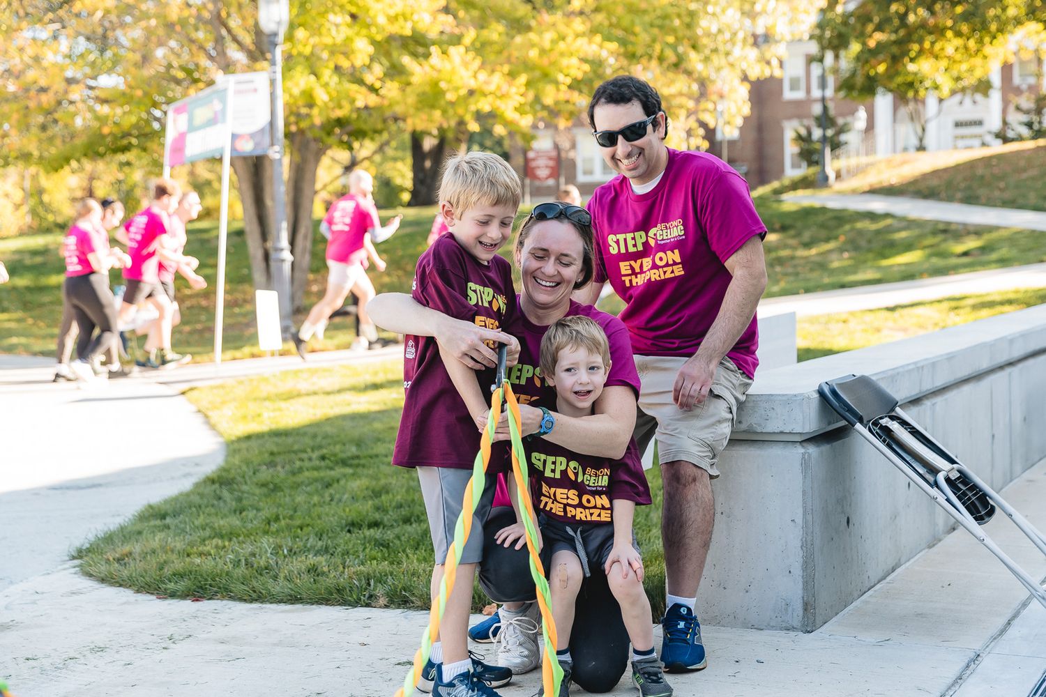 Group in maroon shirts enjoying outdoor activities at a campus event during sunny autumn day.