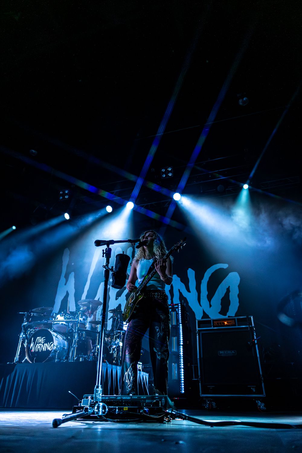 Concert stage bathed in dramatic blue lighting with silhouetted performers and equipment creating an atmospheric scene.