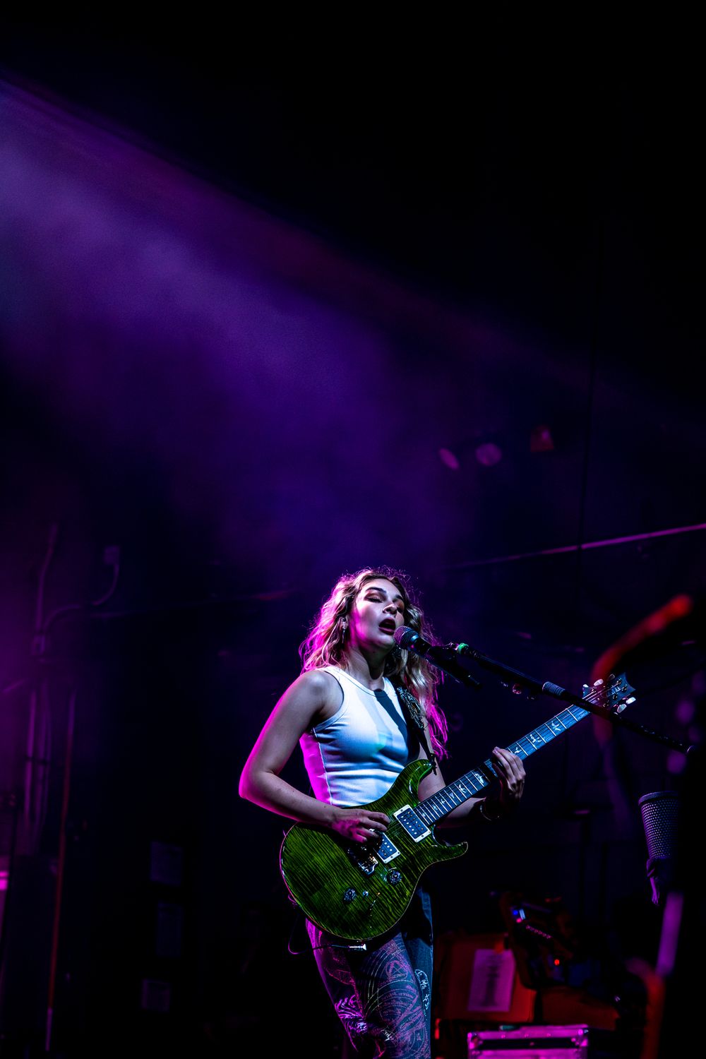 Rock performance on stage with purple mood lighting and atmospheric effects.