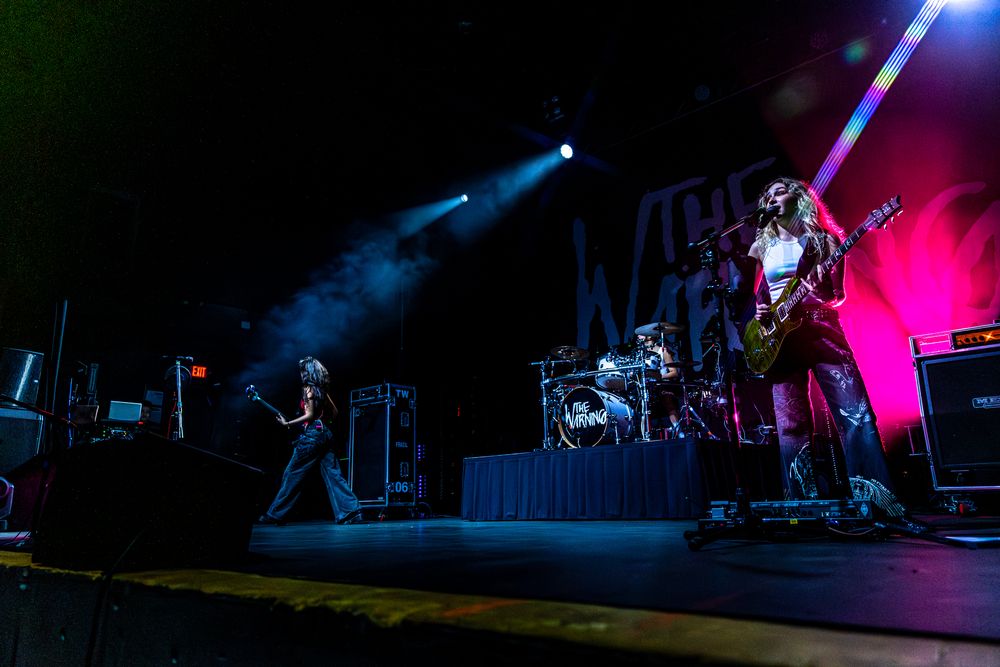 Wide concert stage setup photographed with dramatic blue and red lighting effects creating depth and atmosphere.