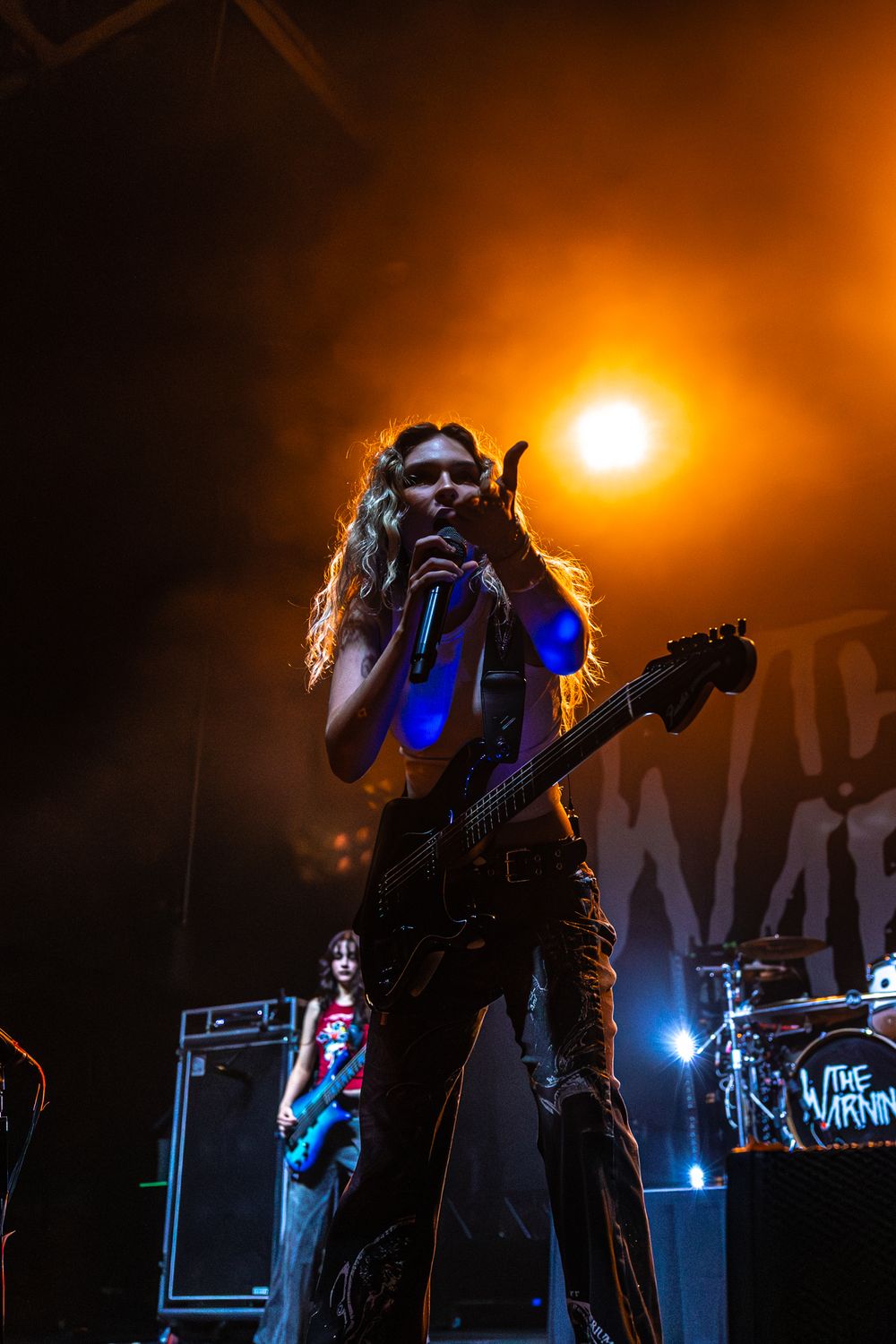 A performer silhouetted against dramatic orange and blue stage lighting during a concert performance.