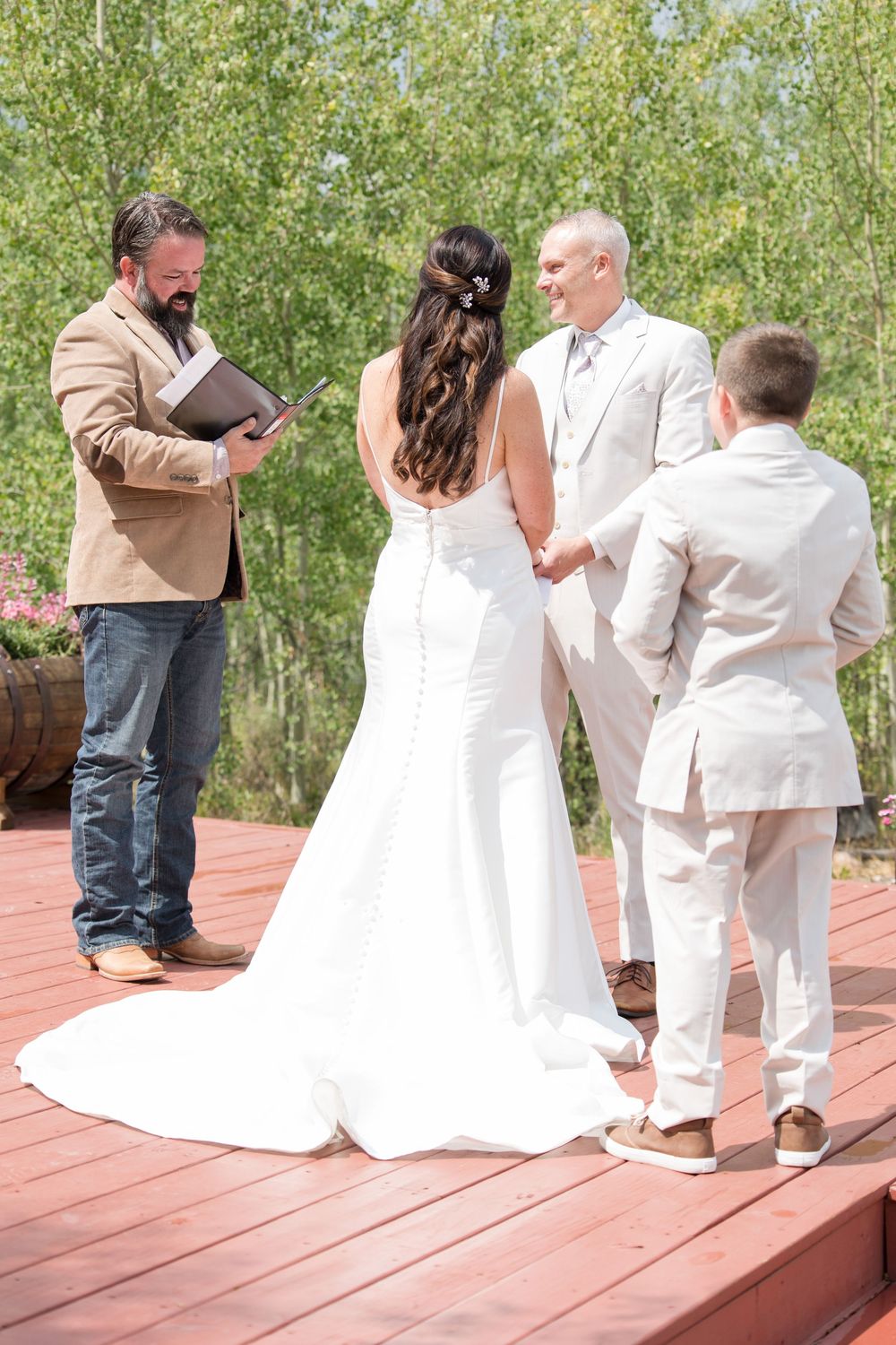A sequence of wedding photos showing a couple and child interacting playfully on a wooden deck with trees in background.