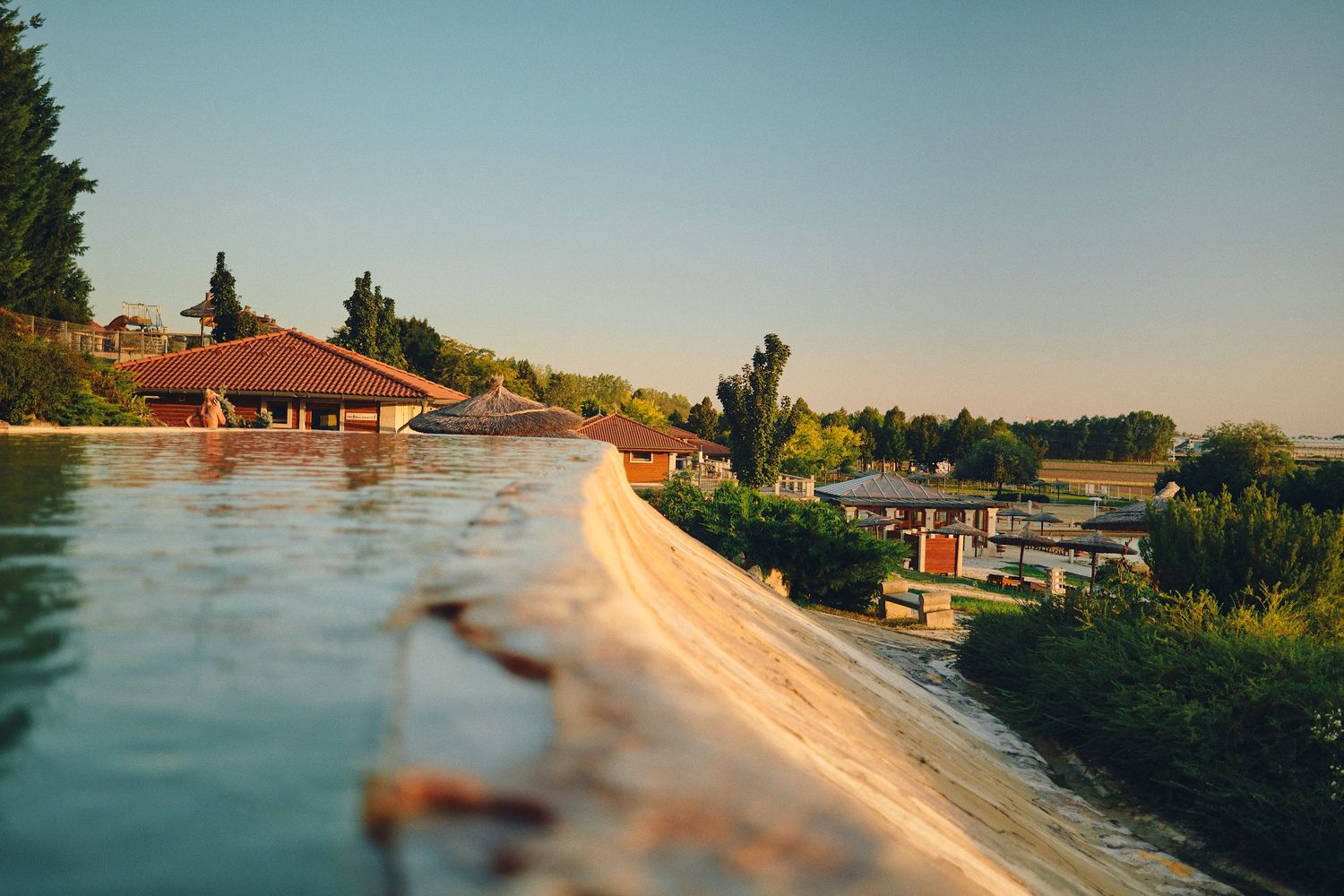 Scenic panoramic view of a lakeside dock at sunset with calm waters reflecting golden light.