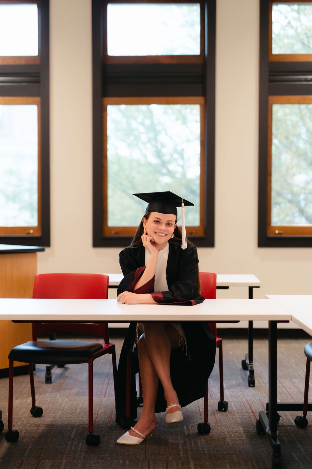 Creative graduation photo series showing poses on classroom furniture.