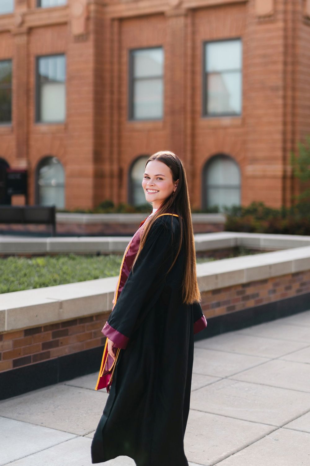 A series of graduation portraits taken outdoors against a brick building backdrop.