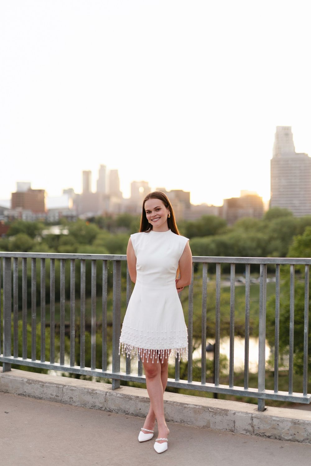 Graduation portraits on a rooftop terrace with city skyline views at sunset.
