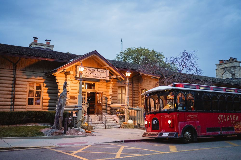 Rustic log cabin wedding venue exterior with warm lighting and red vintage truck parked outside at dusk.