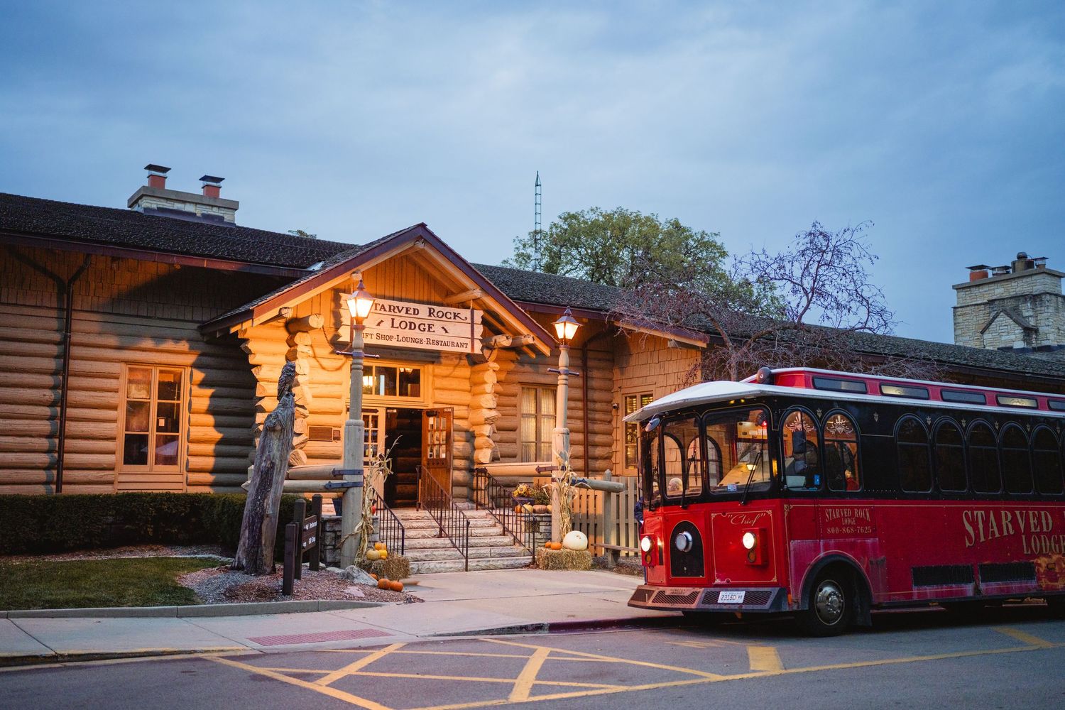 Rustic log cabin wedding venue exterior with warm lighting and red vintage truck parked outside at dusk.